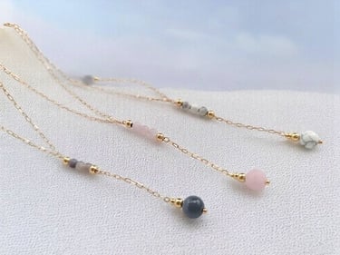 Ensemble de 3 colliers en plaqué or et pierre naturelles, sur du sable