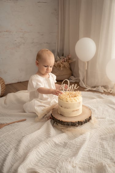 Baby girl celebrating her first birthday with a boho cake smash session and wooden cake topper.