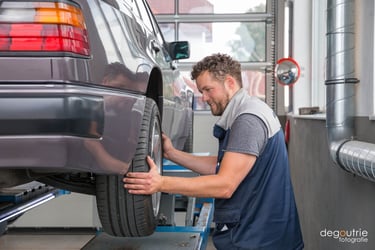Gewerbefotografie in einer Kfz-Werkstatt: Ein Mechaniker montiert einen Autoreifen.