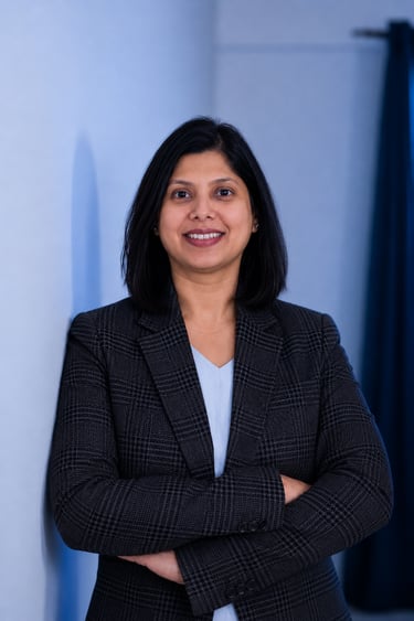 Professional portrait of a female executive in a grey plaid blazer with arms crossed.