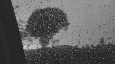 Lluvia cayendo sobre el cristal de un auto en movimiento.