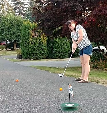 Female street golf player taking a shot with urban golf equipment in neigborhood