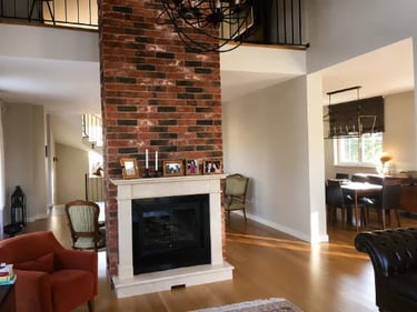 Modern living room featuring a tall red brick fireplace with a white mantel and hardwood floors.