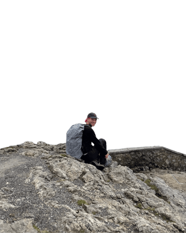 Bild Konstantin Michaelis. Sitzend an einer Mauer. lächelnd