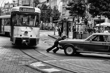 Candid urban scene of car breakdown in front of tram in black and white.