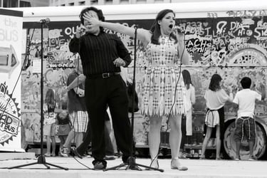 Candid black and white street photo of singer stealing the limelight.