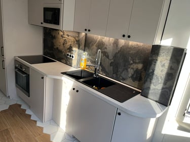 Modern minimalist kitchen with dark marble backsplash, white cabinets, and built-in appliances.