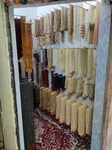 A variety of traditional Indian mala beads and prayer necklaces displayed on a wall in a shop.