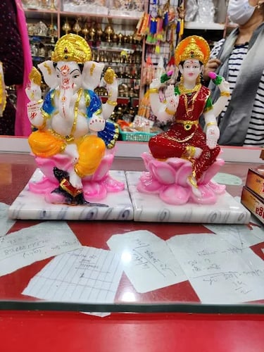 Colorful Lord Ganesha and Goddess Lakshmi marble idols sitting on pink lotus bases for Diwali puja.