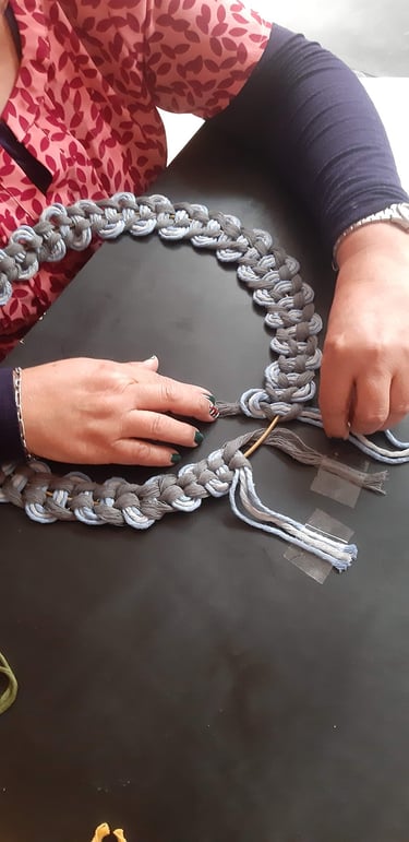 Mujer tejiendo a mano una corona de macramé con cordones de colores