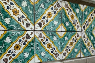 Hand-painted Mediterranean ceramic tiles featuring yellow floral patterns and green scrollwork.