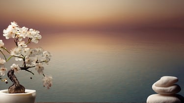 White cherry blossom bonsai tree and stacked zen stones over a calm water background.