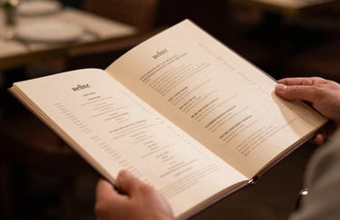 A high-quality photo of a person's hands holding a menu in a sophisticated North American restaurant. The lighting is warm and inviting. No faces are shown, emphasizing the faceless service model.