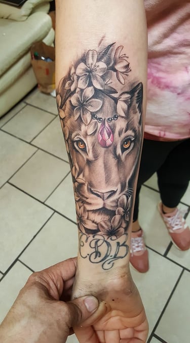 Tatuaje profesional detallado estilo realismo de una leona con flores y diamante rosa Detroit Aztec Tatto Leon Guanajuato