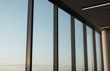 A detailed shot of a modern office interior with large glass windows reflecting soft sky blue light, minimalist aesthetic.