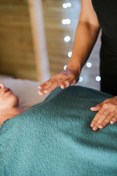 Une femme reçoit une séance de magnétisme, allongée sur une table de massage, détendue et concentrée.