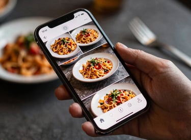 A person's hand holding a smartphone showing a beautifully curated social media feed of gourmet pasta dishes.