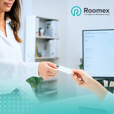 A business traveler checking into a hotel, handing a card to a receptionist for Roomex workforce travel.