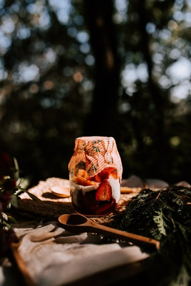 Tarro de mason jar de cristal con yogurt y fresas tapado con una tela encerada o envoltorio de cera 