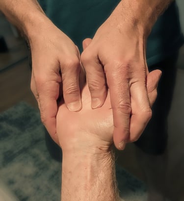 Two hands holding and massaging a third hand.
