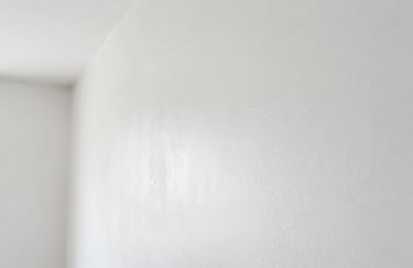 Clean macro shot of fresh white drywall taping work, showcasing a perfectly smooth and seamless finish in a modern Canadian interior, bright and airy lighting.