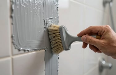 Close-up of a worker's hand applying a professional grey coating to bathroom tiles, focused on the brush and texture, modern finish.