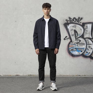 Editorial shot of a male model in urban streetwear against a minimalist city backdrop.