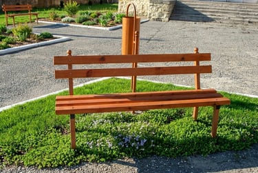 A wooden park bench with backrest on green grass in a public garden area.