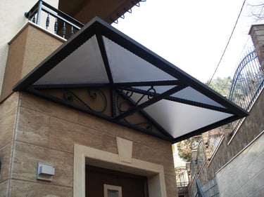 Modern wrought iron door awning with frosted glass panels installed over a home entrance.