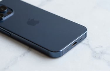 Close-up photography of a high-end smartphone with a matte deep navy finish resting on a clean white marble surface. Soft, professional lighting. Global / Tech-focused.