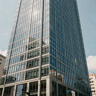 Photography of a modern office building in a South American / Brazilian city, focusing on the professional architecture and clean glass panels. Natural daylight.