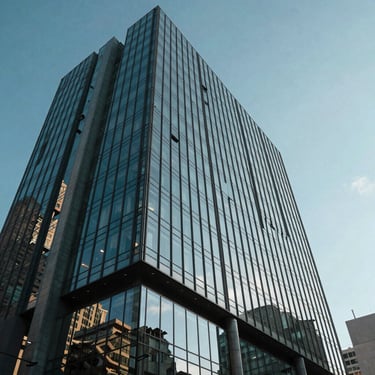 Low angle shot of a contemporary glass office building in a major Hispanic metropolitan area, reflecting a clear blue sky, emphasizing corporate trust and scale.