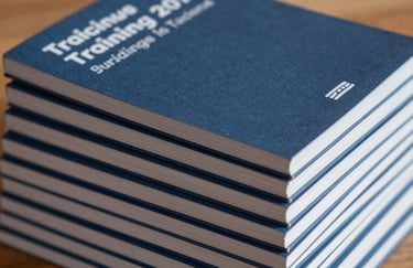 A collection of training manuals stacked neatly, showing spines in shades of slate midnight blue and soft silver blue.