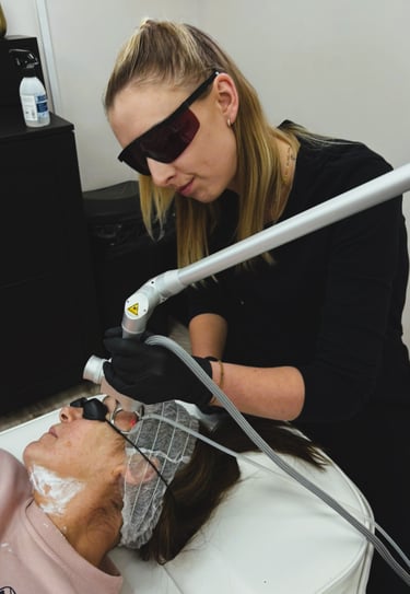 Professional esthetician performing a laser facial treatment on a patient for skin rejuvenation.