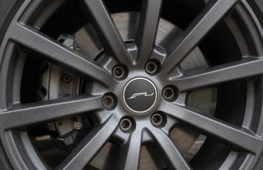 A detailed view of a multi-spoke alloy wheel with a matte charcoal finish, crisp focus on the brand emblem, professional North American studio lighting.