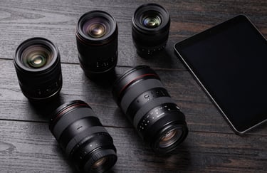 A sophisticated flat-lay photography of high-end camera lenses and a professional tablet on a Dark Charcoal wooden desk. High-contrast lighting highlights the textures in a North American studio.