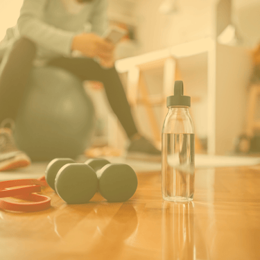 Person on exercise ball with dumbbells and water bottle
