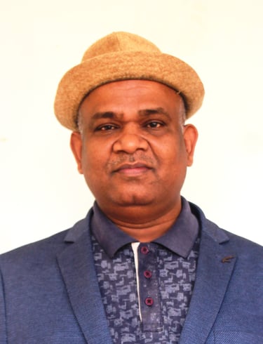 Professional portrait of a man wearing a blue blazer, polo shirt, and a stylish tan fedora hat.