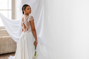 Une femme de dos en robe de mariée blanche un bouquet de fleurs à la main