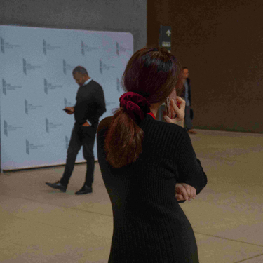 Woman with red hair-tie talking on phone with back to camera.