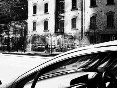 The foreground is a car; the background is a person walking against old wall.