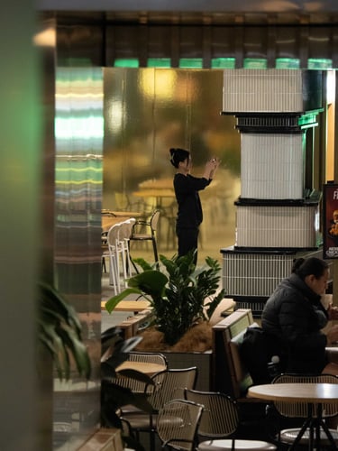 A young woman takes a photo in a cafe.