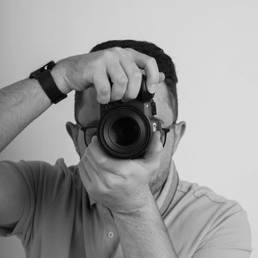 Photographe professionnel tenant un appareil photo hybride pour une séance de portrait.