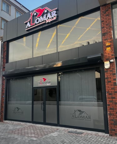 Modern Alomar Insaat construction office storefront with large glass windows and red brick accents.