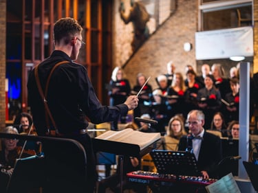 An over the shoulder photo of a maestro directing an orchestra