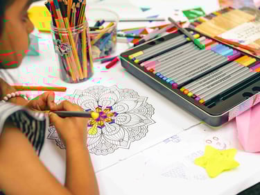 An over the shoulder photo of a girl colouring a mandala