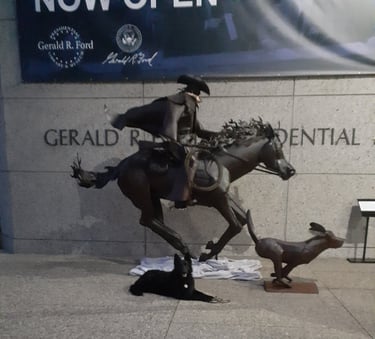 Dog lying calmly at the Gerald R. Ford statue in Grand Rapids, MI, demonstrating 'Foundations' IRL