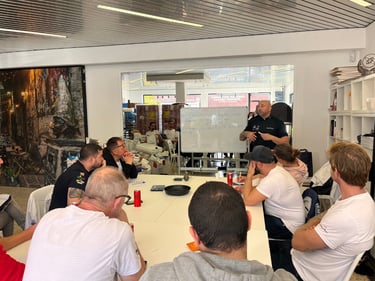 Professional chef leading a culinary training workshop with students around a conference table.