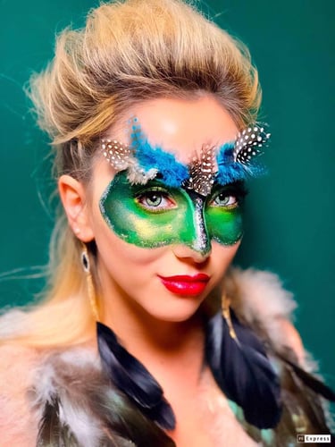 Model wearing creative green bird-inspired mask makeup for a costume makeup look.