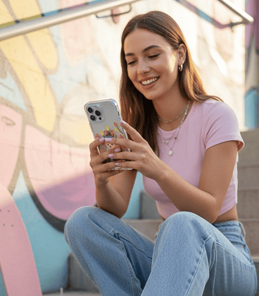 Mujer sonriente con blusa rosa usando una funda pintada floral al aire libre